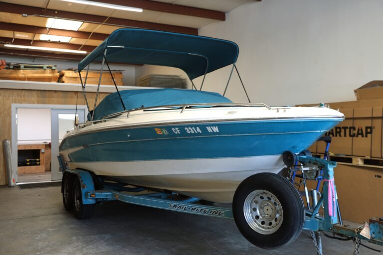 A blue and white boat on a trailer with a Bimini top